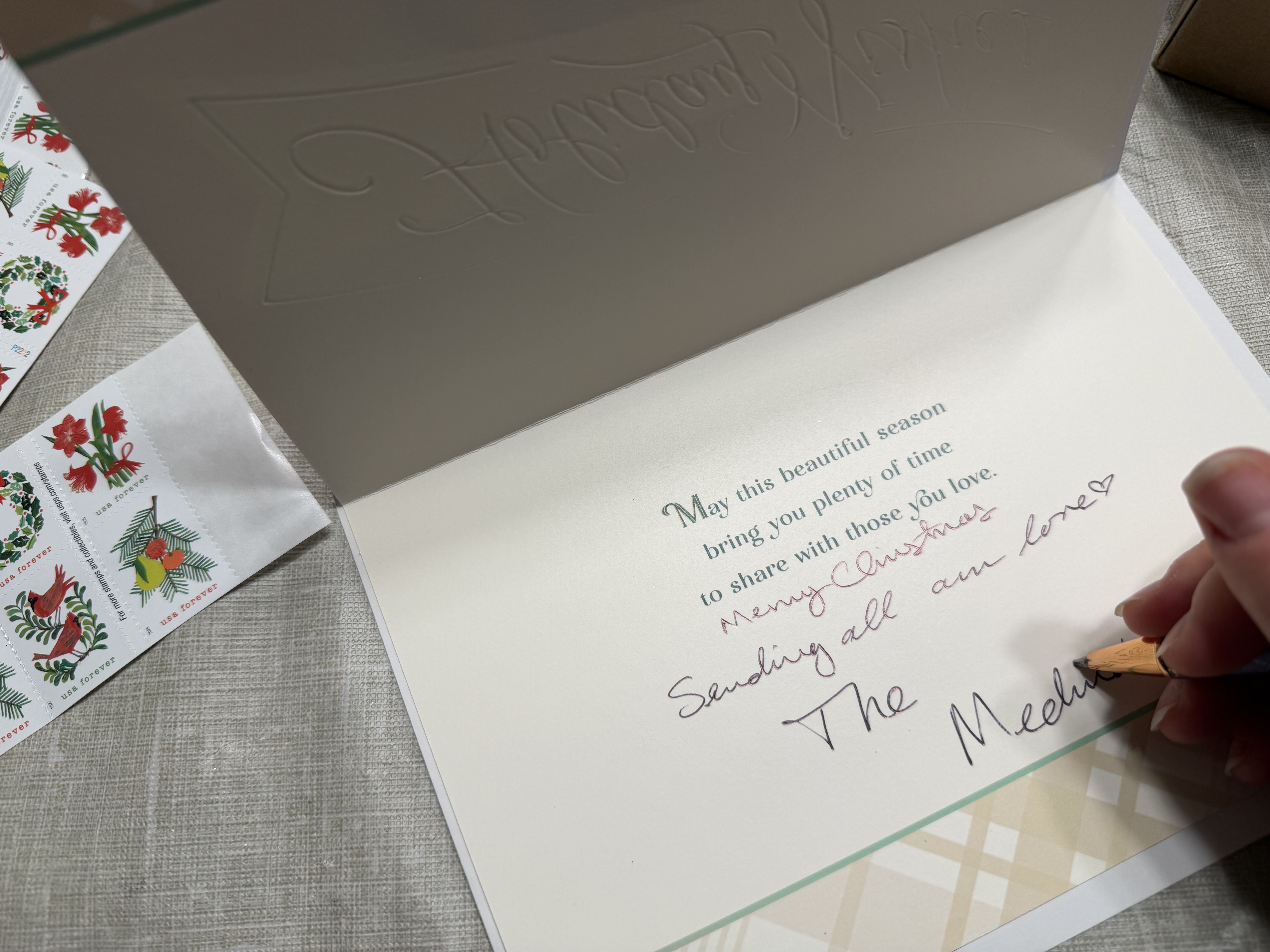 Annabrodea sitting at a table writing Christmas cards